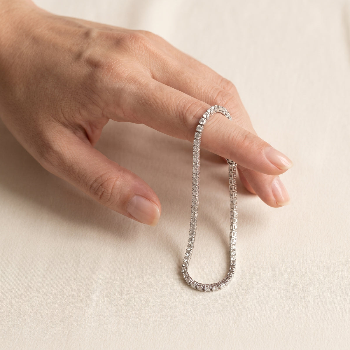 Starfall tennis bracelet hanging from a finger to show its size
